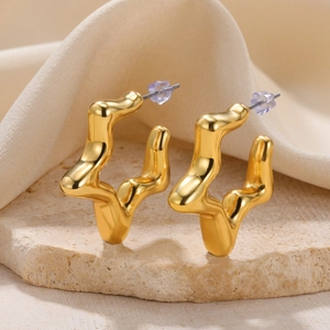 Detailed view of gold irregular wavy lava earrings on a stone base with silk fabric
