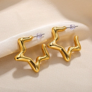 Macro detail of gold star-shaped earrings with irregular wavy edges and mirror finish