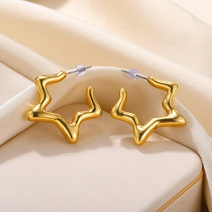 Detail of star-shaped golden hoop earrings with high polish finish on cream silk fabric