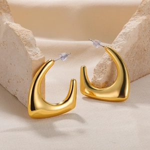 Detailed macro view of polished gold crescent moon earrings on a textured stone prop