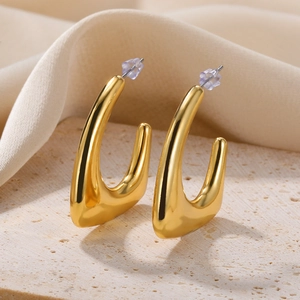 Detailed close-up of golden teardrop-shaped metal earrings on a natural stone base