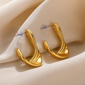 Macro detail of gold U-shaped earrings with high-polish finish on elegant silk background