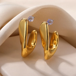 Detailed macro view of irregular gold C-shaped earrings with high polish liquid metal finish