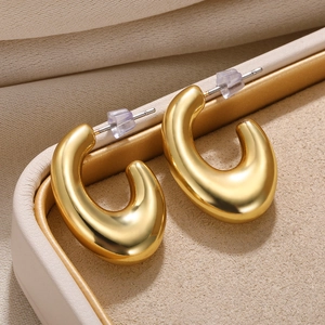 Close-up of golden teardrop C-shape earrings with high-polish finish on a jewelry tray