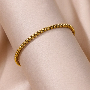 Macro shot of gold-plated box chain on champagne silk showing premium metal texture