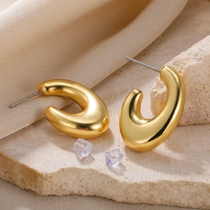 Detailed close-up of golden C-shaped hollow earrings with clear flower silicone backings