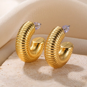 Detail of gold C-shaped hoop earrings with textured spiral ridges and luxury finish