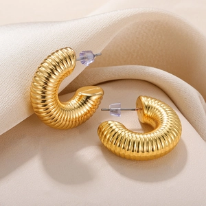 Close-up of golden hollow crescent hoop earrings with textured horizontal ribbed finish