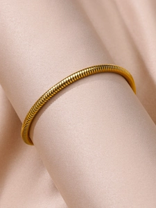 Detail shot of a flexible golden 18k gold plated stainless steel anklet on silk
