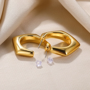Detailed view of chunky gold geometric hollow moon earrings on beige satin fabric