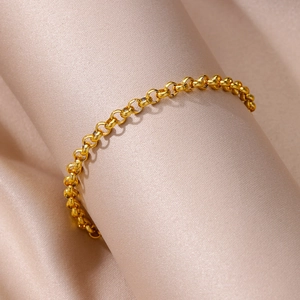 Close-up of golden rolo chain anklet on elegant champagne silk fabric with soft shadows