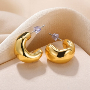 Macro shot of thick gold C-shaped hoop earrings with polished finish and silicone backings