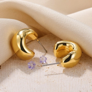Close-up of chunky gold C-shaped hoop earrings with lavender flower petal backings