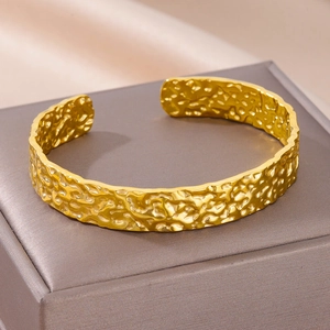 Macro-detail van de gouden gehamerde textuur op verstelbare minimalistische C-armband