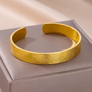 Detailopname van een gouden hamertextuur armband op een zijden sieradenkussen in doos