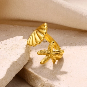 Detail of gold starfish and seashell textures on an adjustable open ring over natural stone