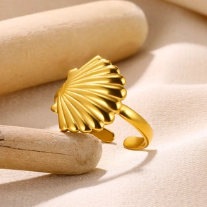Macro shot of gold-plated scallop shell ring with textured surface on wooden stand