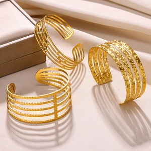 Three-piece set of textured gold-plated stainless steel open bangles on satin background