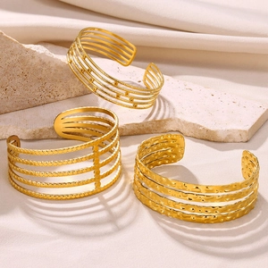 Detail of three gold plated stainless steel open bangles with unique textured patterns