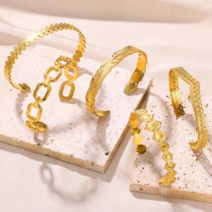 Detail of five gold stainless steel bangles with snake and geometric engraved patterns