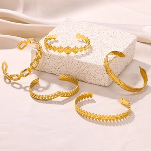 Five-piece gold stainless steel open bangle set with geometric, feather, and leaf designs