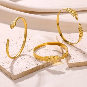 Detailed view of three gold-plated stainless steel open bangles with snake and leaf patterns
