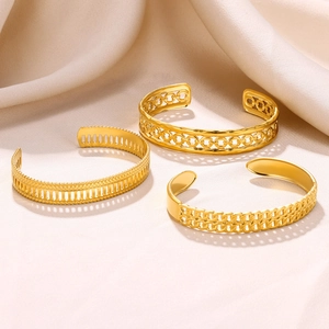 Detailed close-up of three gold open bangles with hollow, grid, and braided textures