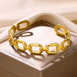 Detailed close-up of golden oval link cuff bracelet on luxury champagne silk fabric