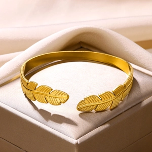 Detailed close-up of golden stainless steel open bangle with intricate feather-shaped ends
