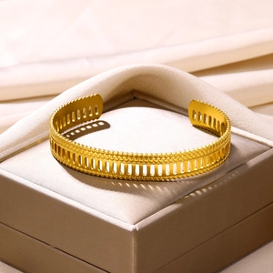 Detail of gold-plated stainless steel open cuff with hollow vertical grid and beaded edges