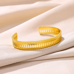 Macro shot of gold plated stainless steel open bangle with vertical stripes and beaded edges