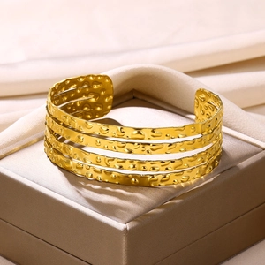 Detailed macro of gold-plated multi-layer cuff bracelet with a hammered metal texture