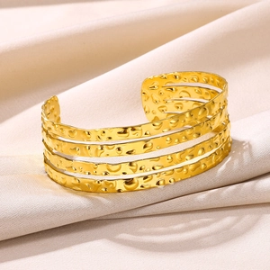 Detail of gold-plated open bangle featuring four parallel layers with hammered metal texture
