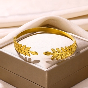 Detail of 18K gold plated wide cuff bracelet featuring hollow olive leaf pattern