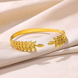 Detailed view of golden leaf motif on a stainless steel open cuff bracelet