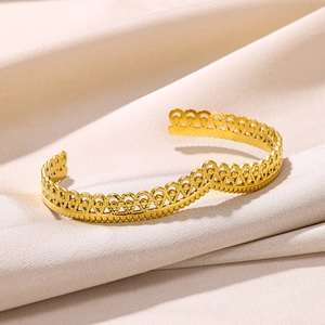 Close-up of gold stainless steel open cuff bracelet with wavy lace cutout patterns