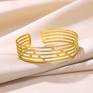 Detail view of gold snake-style cuff bracelet with textured bands and small sphere accents