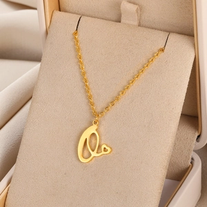 Vue macro du pendentif lettre L dorée avec cœur évidé sur une fine chaîne maille forçat