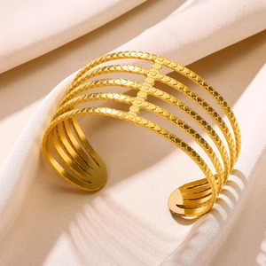 Detail of five-layer gold plated stainless steel open bangle with textured dot patterns