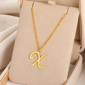 Détail d'un pendentif cœur avec lettre X dorée présenté sur un support de bijoux en velours