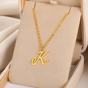 Détail du pendentif lettre K dorée avec petit cœur présenté dans un écrin à bijoux élégant