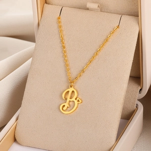 Détail d'un collier doré avec pendentif lettre B et petit cœur dans un écrin à bijoux