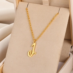 Gros plan du collier en acier doré avec pendentif lettre J et cœur dans un écrin cadeau