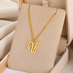 Détail macro du pendentif lettre V dorée avec motif cœur sur une chaîne élégante
