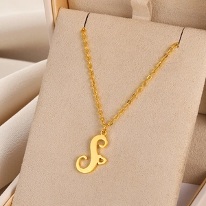 Gros plan du collier en acier doré avec pendentif lettre S et découpe en forme de cœur