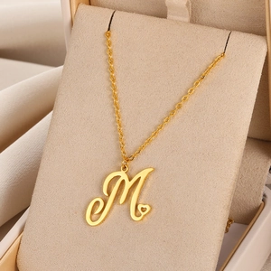 Détail du pendentif lettre M doré avec cœur évidé sur une chaîne minimaliste