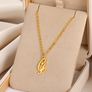Vue macro du collier doré avec pendentif lettre et cœur sur doublure en velours beige