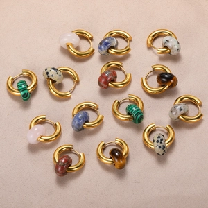 Golden donut earrings set with natural stones like malachite and tiger eye on linen