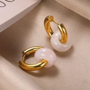 Detail of gold donut hoop earrings with white translucent stone charms on silk fabric