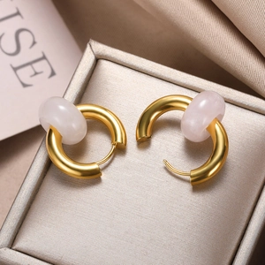 Detail of golden donut hoop earrings with translucent pink natural stone on silk